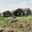 View from NE showing collapsed and standing asbestos roofed huts.