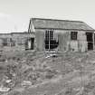 View fom E showing standing remains of asbestos roofed hut with timber extension.