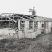 View from SE of a surviving hut showing timber framing used in construction and recent use as animal pens.