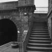 Station: detail of abutment of road bridge over railway, with stair up to bridge from Platform 2 of station
