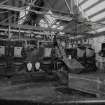 Interior view of boiler house showing two main boilers with semi-automated coal feed.  Also visible is a electrical wall panel and the steel roof trusses.