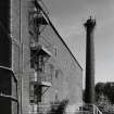 View from W along SE side of warehouse No 6 with boiler-house chimney.