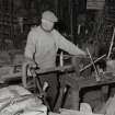 Smiddy, Emil Kozoki, blacksmith, at work on bending machine