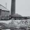 View of kilns and chimney stack behind.