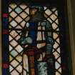 View of reused stained glass window depicting a knight to West of the organ.