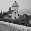 View of lighthouse and N gable of cottage from ENE