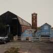 General view from SW of SE side of four-storeyed polychrome- brick mill (E mill) and tower, and single storeyed buildings at E side of works.  Photosurvey 22-APR-1992