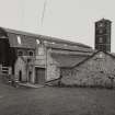 General view from S of SE side of four-storeyed polychrome- brick mill (E mill) and tower, and single storeyed buildings at E side of works.  Photosurvey 22-APR-1992