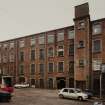 View from NE across wedge-shaped yard towards E elevation of polychrome-brick four-storeyed mill ( W mill).  Photosurvey 22-APR-1992