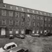 General view from NW across wedge-shaped yard of NW elevation of polychrome-brick four-storeyed mill ( E mill).  Photosurvey 22-APR-1992