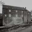 View of mill from SE, showing lade and water wheel on left, mill in centre and one of the two kilns on right.