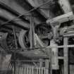 Interior. ground floor of mill, view from NE of part of a long of over-head line-shafts and pulleys taking power from the water wheel to various machines throughout the mill