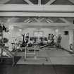 Interior view from N showing modern gym equipment within mid-19th century building.
