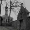 View from S from street showing cross-finialled crowstepped entrance to burying ground of Macpherson family to right