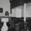 Interior. Detail of pews and octagonal stone font