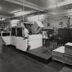 Case Erection: View from E of case erection machine providing assembled Dewar's White Label boxes (for 12 boxes) for Line No. 4 in Bottling Hall below.
Photographed 27 January 1994