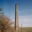 View from NW of tapered, square-section fireclay brick chimney stack, forming part of the remains (otherwise mostly concrete foundations) of the recovery Ether Plant (NY 342 673)
