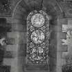 Interior. North chapel, stained glass window on north wall showing scenes from the life of Christ.