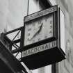 Detail of west face of clock over shopfront of 48 George IV Bridge. Clock bears the legend 'TOBACCOS MACDONALD'. Clock manufactured by Smiths English Clock Systems, London.