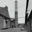 View from S of E gable of boiler house, and of circular-section brick-built boiler-house chimney