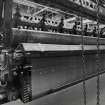 Interior.  Detailed view showing wire cloth emerging from a loom in the Broadloom Weaving Department