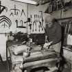 23B Howe Street, interior
View of man using snips on work bench in front shop