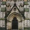 View of gabled doorway framed by niches and buttresses in aisle flanking length of nave.