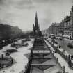 General view along Princes Street with Scott Monument in centre, also showing trams, awnings on shop fronts and horse and carriages