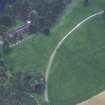 Oblique aerial view centred on the cropmarks of the country house with cathedral adjacent, taken from the NNE.